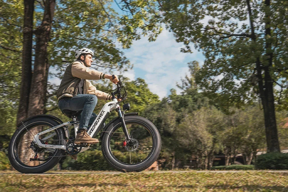Man riding RZOGUWEX S7 fat tire electric bike through green woodland park