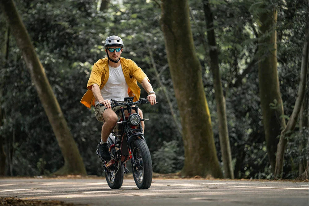 RZOGUWEX X7 rugged off-road e-bike being ridden through a sunlit forest path.
