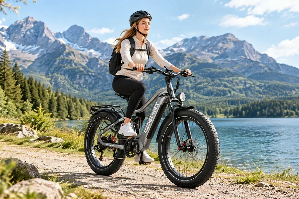 Woman riding RZOGUWEX S7 fat tire electric bike along lakeside mountain trail.