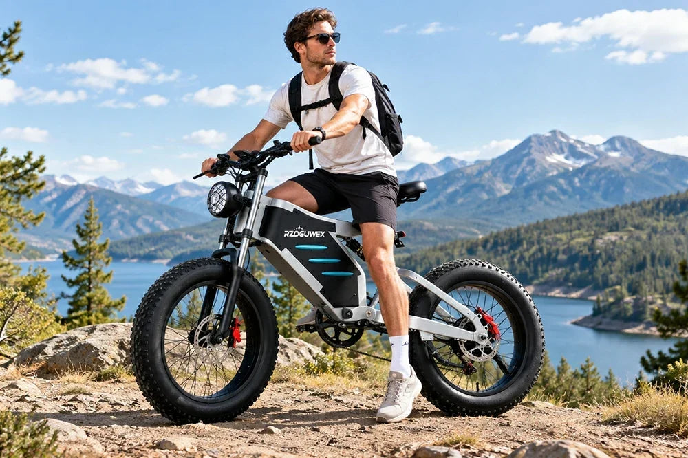 Man riding RZOGUWEX X5 fat tire electric bike on mountain overlook with lake and mountain backdrop
